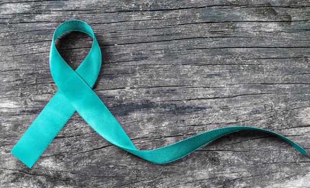 Teal sexual assault ribbon on a wood grain background